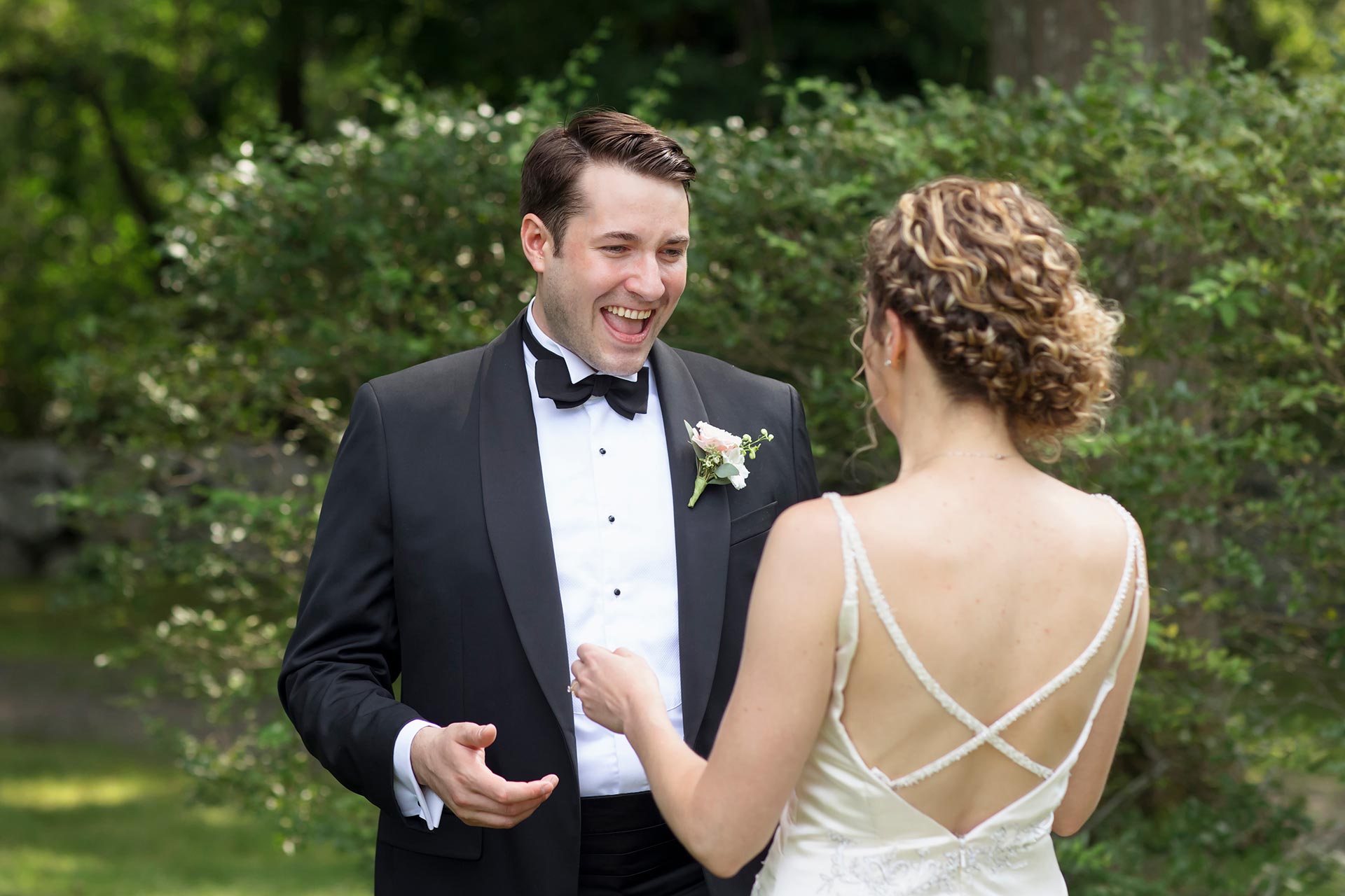 A groom's smiling face upon seeing the bride during a "first look" before their wedding Ceremony. First looks are a great way for couples to make sure that they get to spend the most time with their guests.