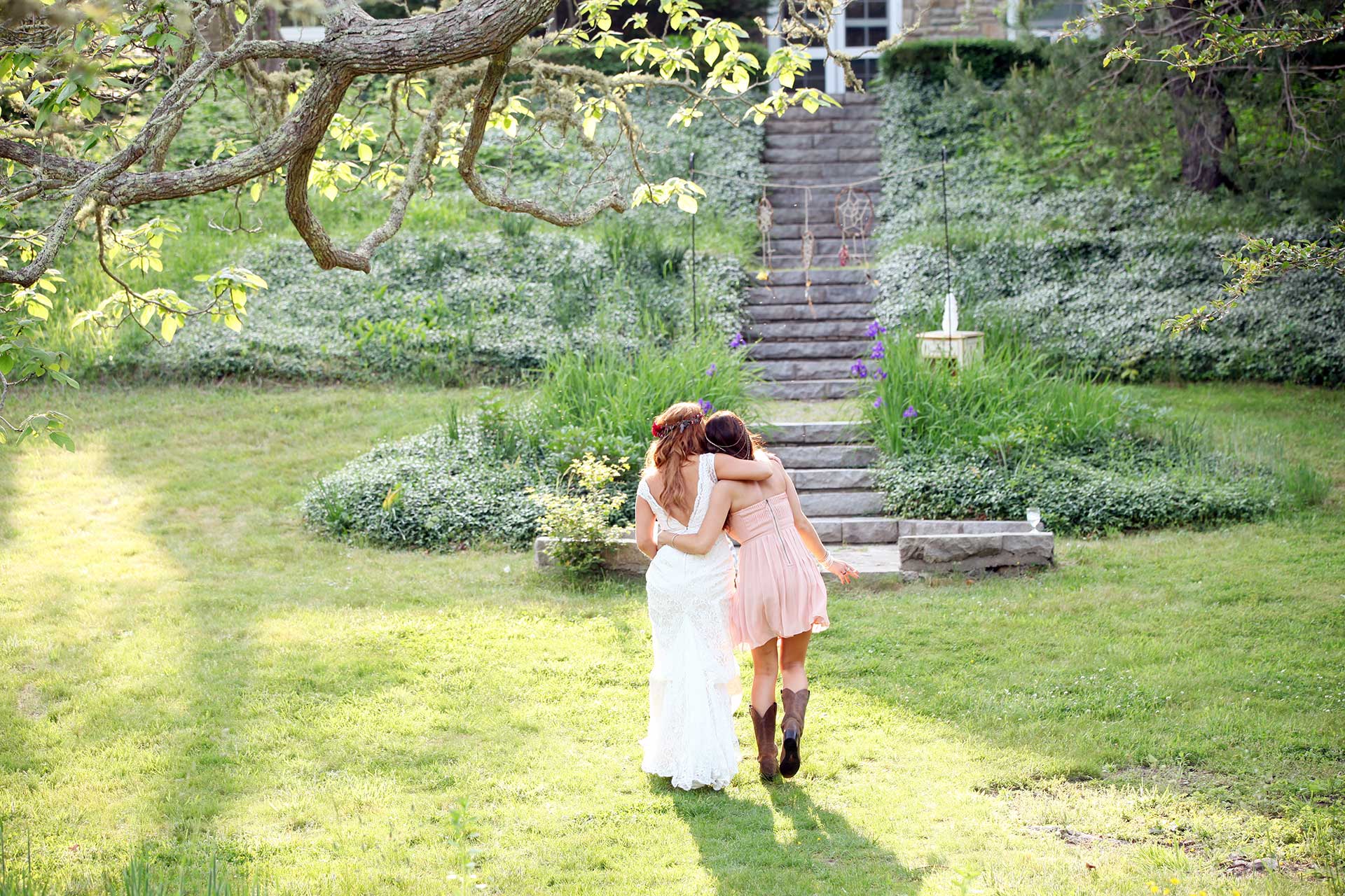 A bride and her best friend hugging during the golden hour at a Cape Cod wedding.