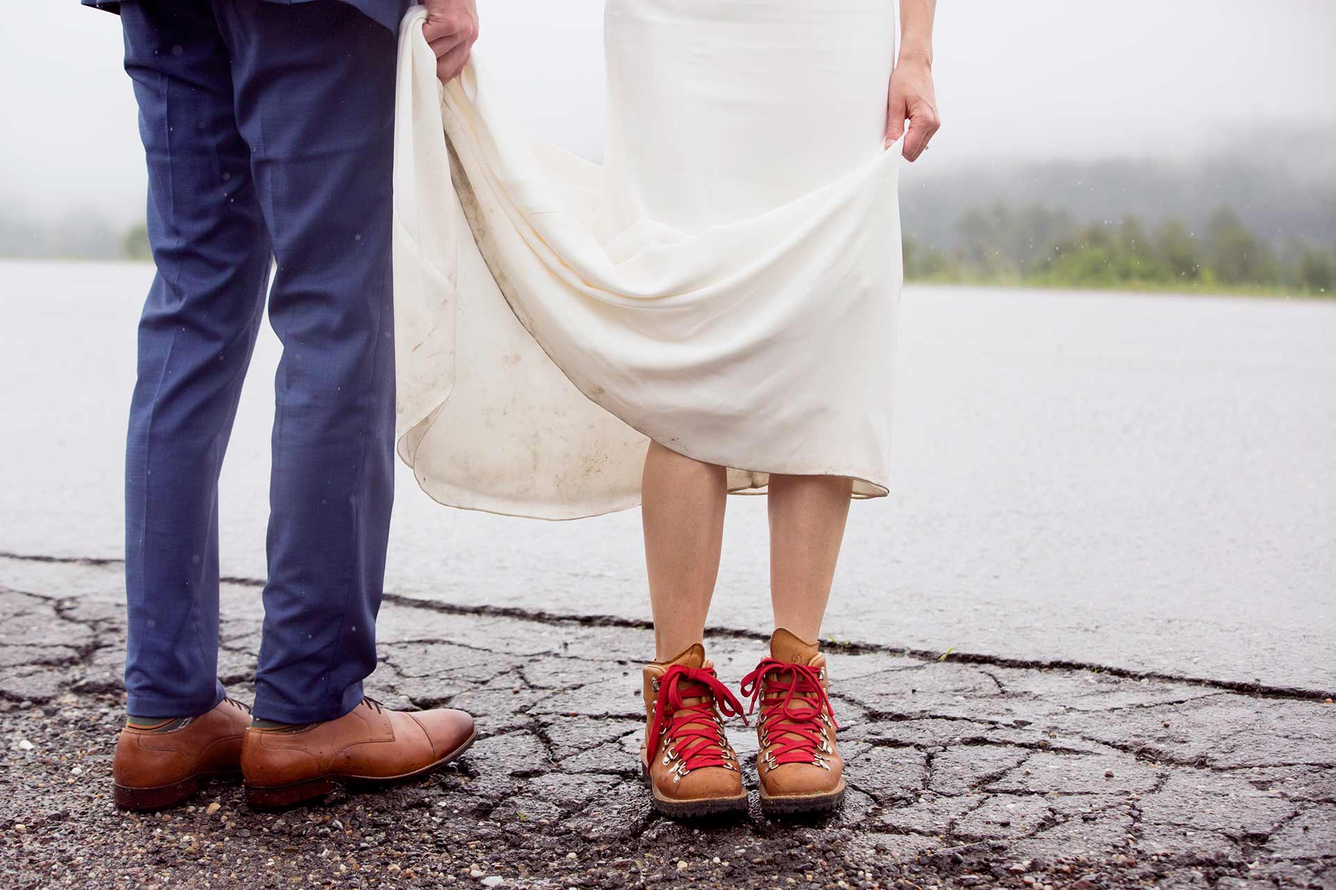 A bride rocking hiking boots on a wet rainy day.